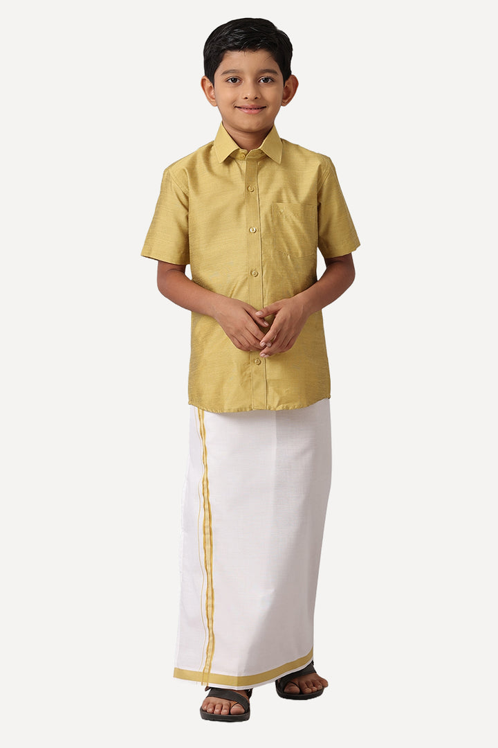 A boy wearing a golden yellow shirt and white dhoti with golden matching borders.