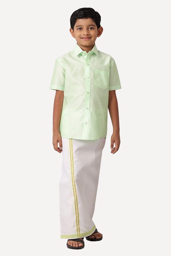 A kid in pale green shirt and white dhoti with white background.