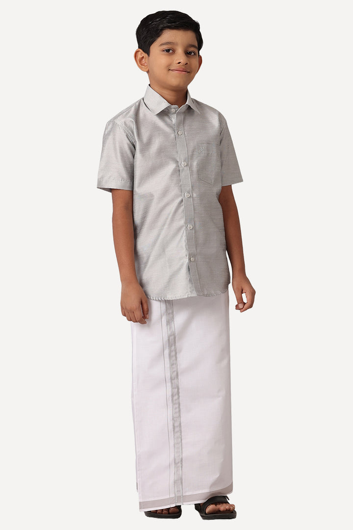 A boy wearing a gray shirt with half sleeves and a matching dhoti set