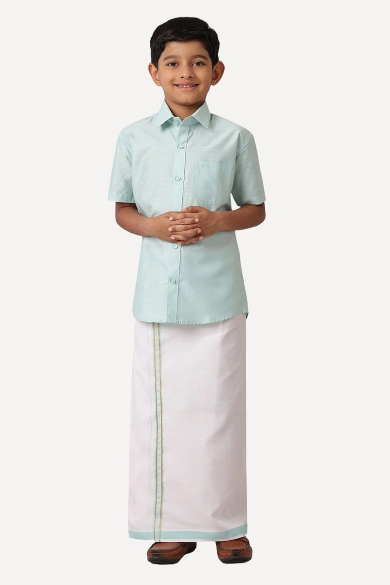 A boy wearing a peach green shirt with half sleeves and a matching dhoti set
