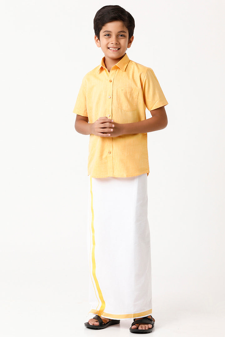 A boy wearing a yellow shirt and white dhoti with yellow border.