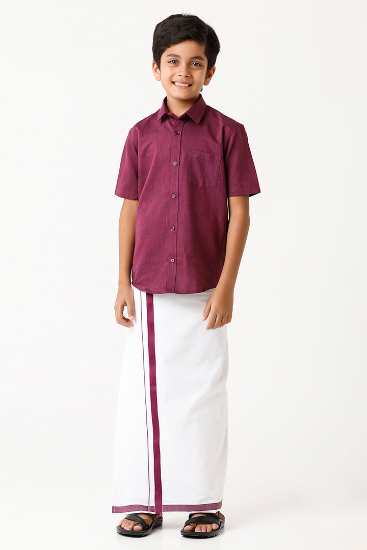 A boy wearing a purple shirt and a white dhoti with a purple border.