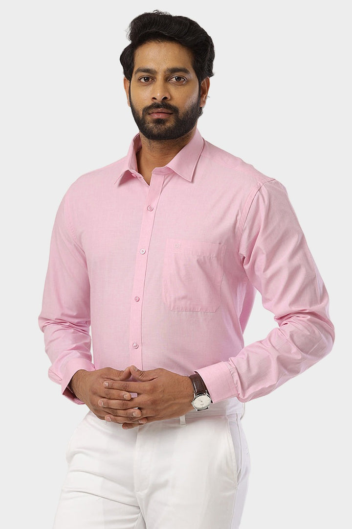 A man wearing a soft pink, solid color, formal shirt with a smart fit and arrow cut bottom.