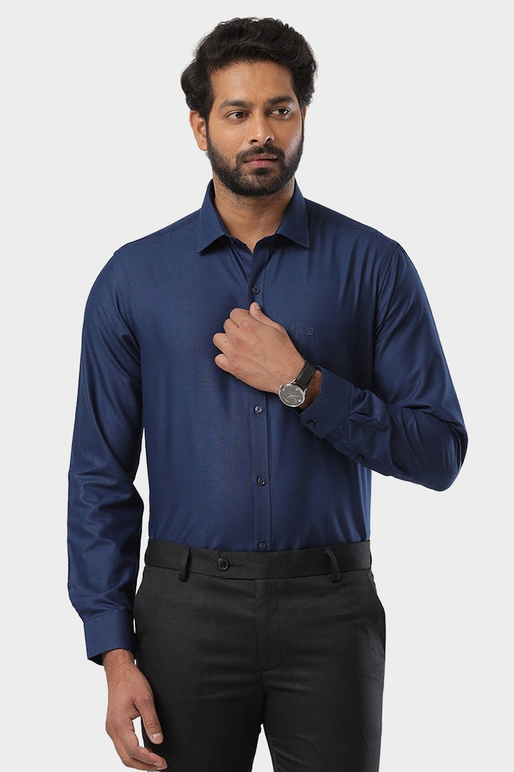 A man wearing a navy blue, solid color, formal shirt with full sleeves and a collar.