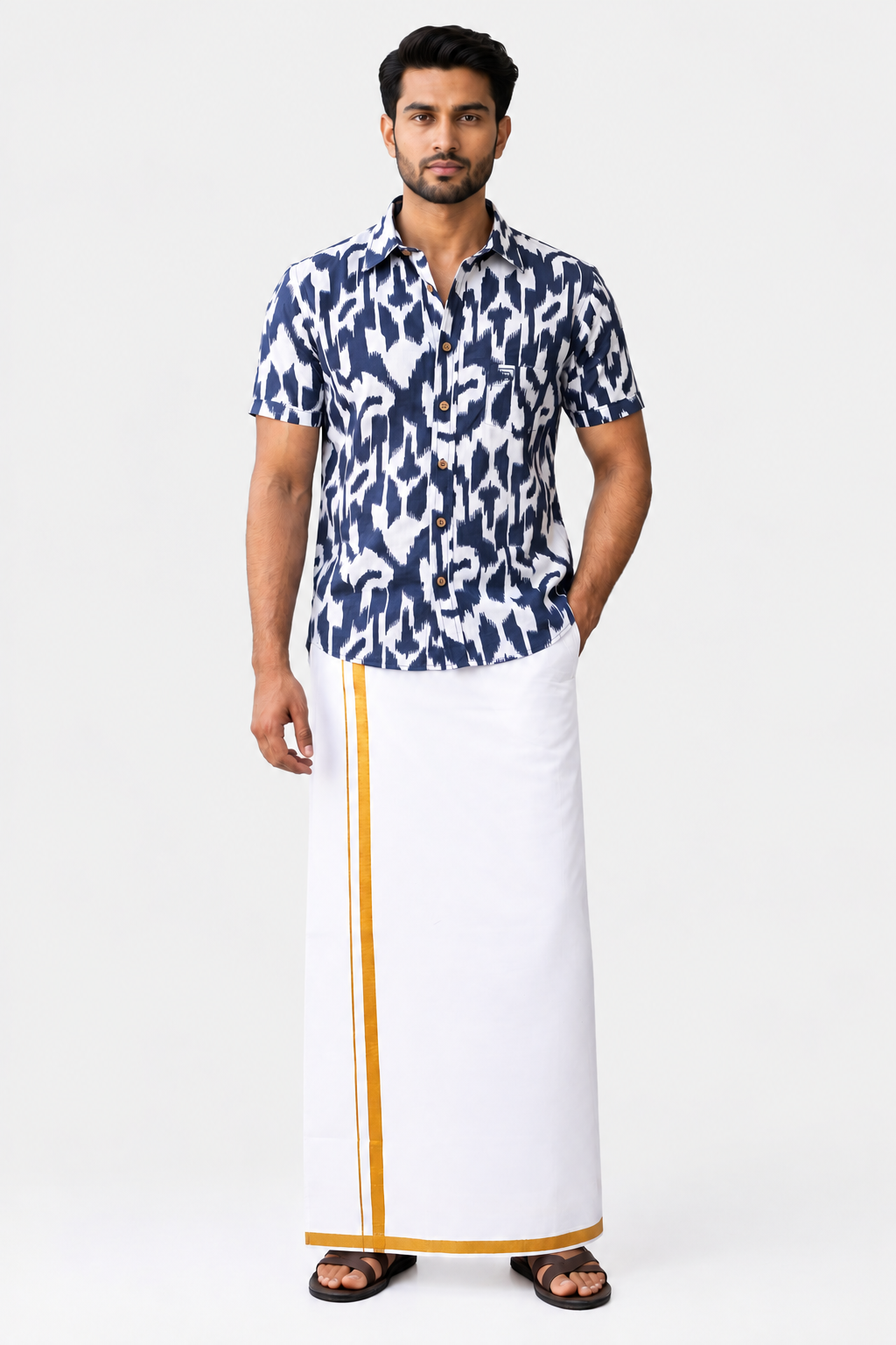 A man modeling a traditional Indian outfit consisting of a navy blue and white patterned short-sleeve shirt and a white drape (kurti) with gold stripes, paired with black sandals, against a plain white background.