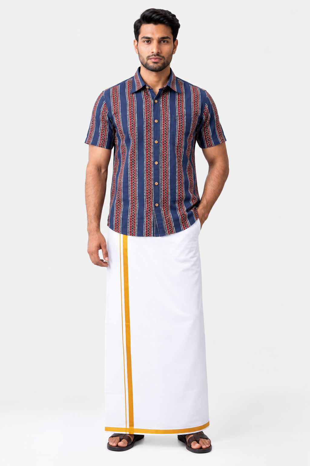 A man modeling a short-sleeve button-up shirt with vertical navy, red, and gold patterns, paired with a white traditional wrap skirt featuring a gold stripe, on a light gray studio background.