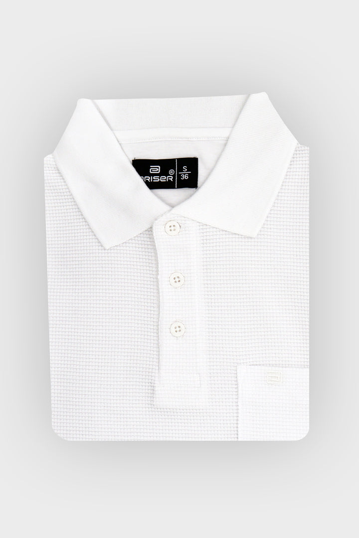 A folded white polo shirt with a subtle micro-check pattern, featuring a classic collar, three-button placket, and a left chest pocket, shown on a light gray background.