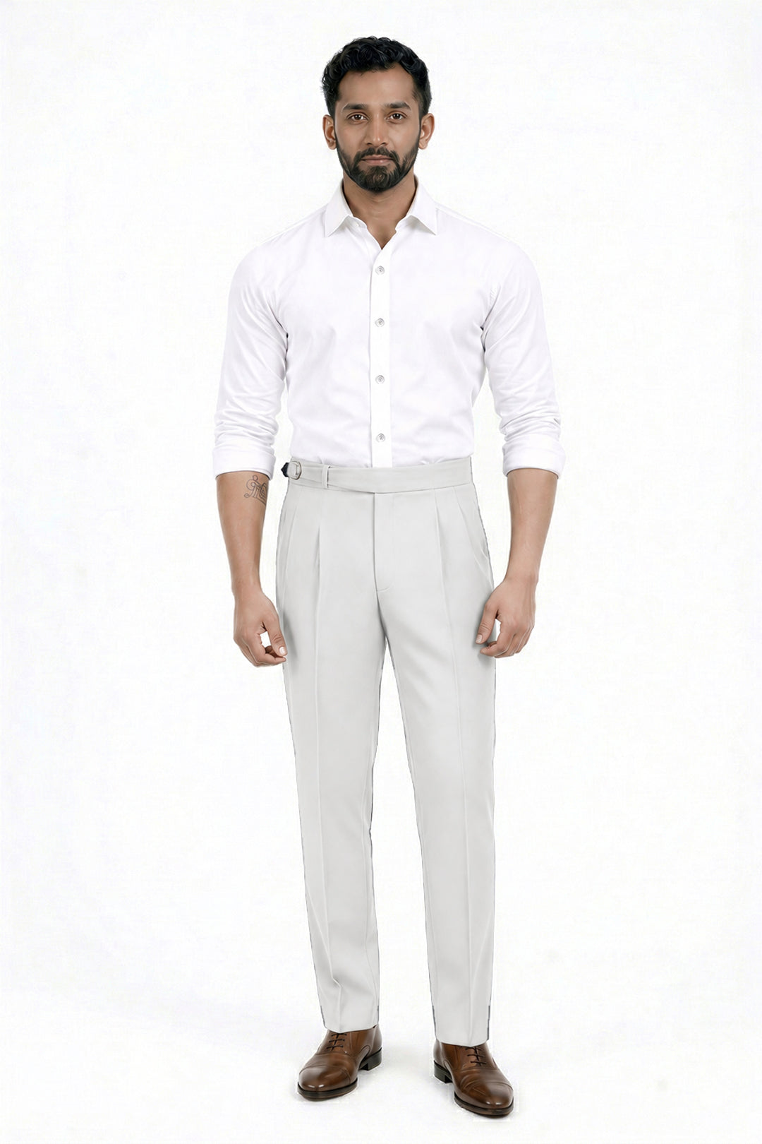 A man modeling a white long-sleeve button-down shirt and light beige trousers with brown dress shoes, standing against a plain white studio background.