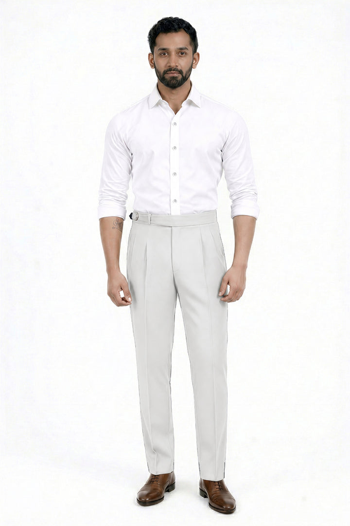 A man modeling a white long-sleeve button-down shirt and light beige trousers with brown dress shoes, standing against a plain white studio background.