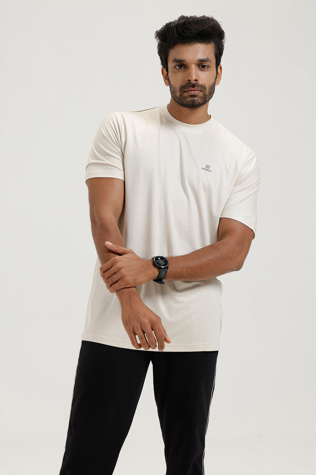 Man wearing a white t-shirt and black pants on a light gray background