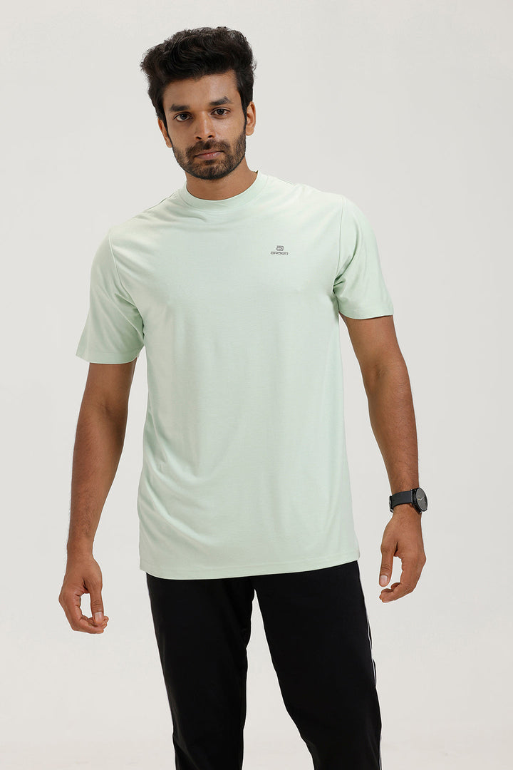 Man wearing a light green t-shirt and black pants on a white background