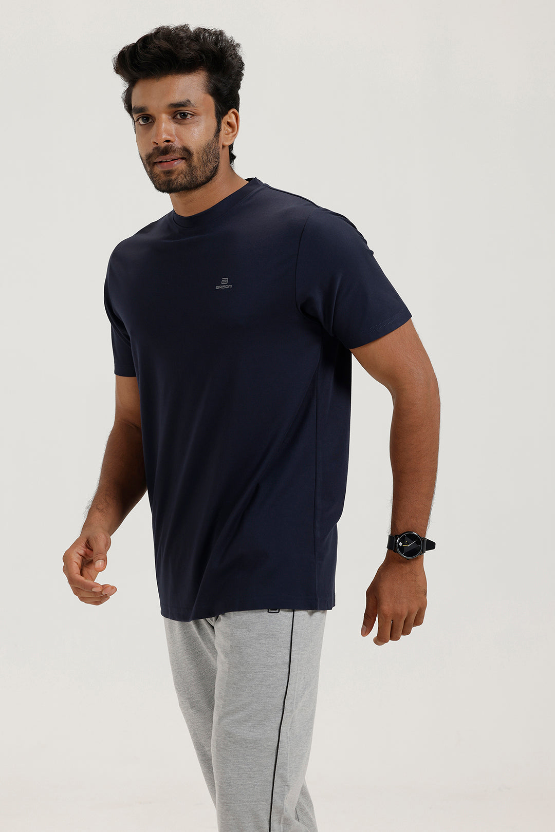Man wearing a navy blue t-shirt and gray pants on a white background