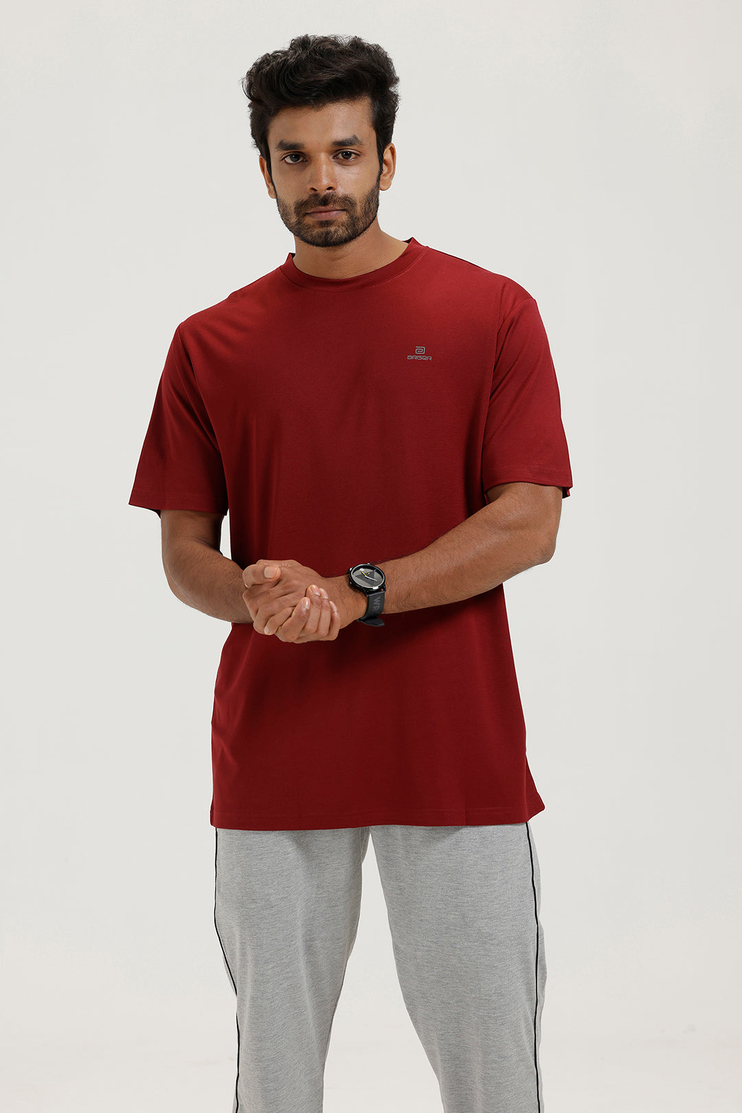 Man wearing a red t-shirt and gray pants on a white background