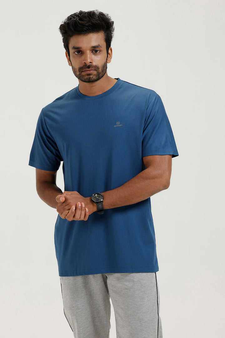 Man wearing a blue t-shirt and gray pants on a white background