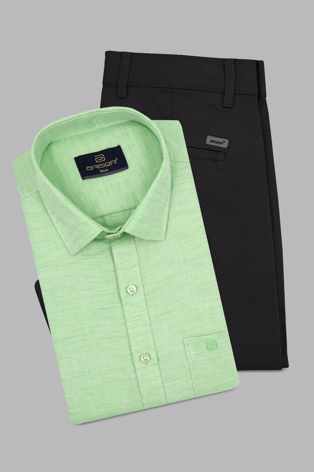 Folded green shirt and black pants on a gray background