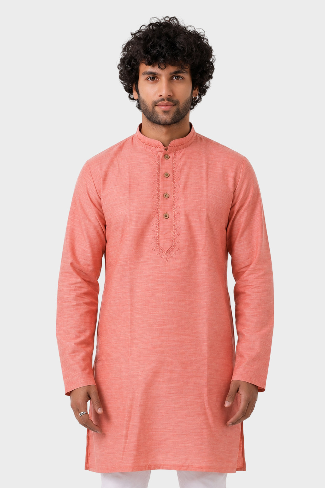 A man wearing a peach-colored long-sleeve kurta with a mandarin collar and three-button placket, standing against a light gray studio background.