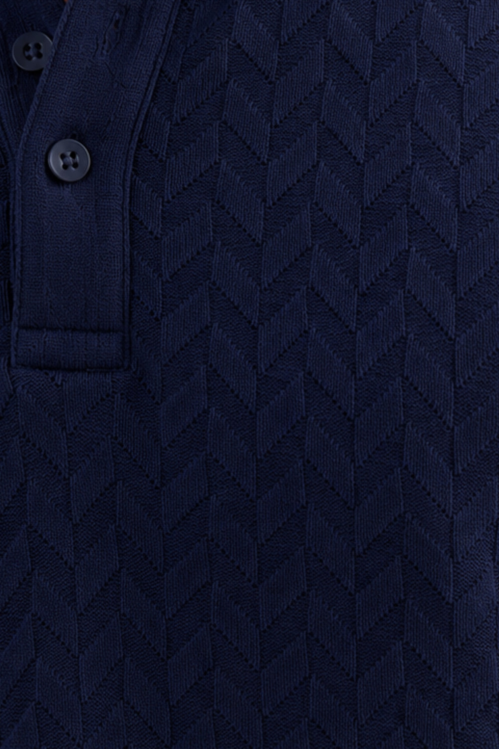 Close-up of a dark navy blue textured knit polo shirt showing a buttoned collar and a chevron pattern.
