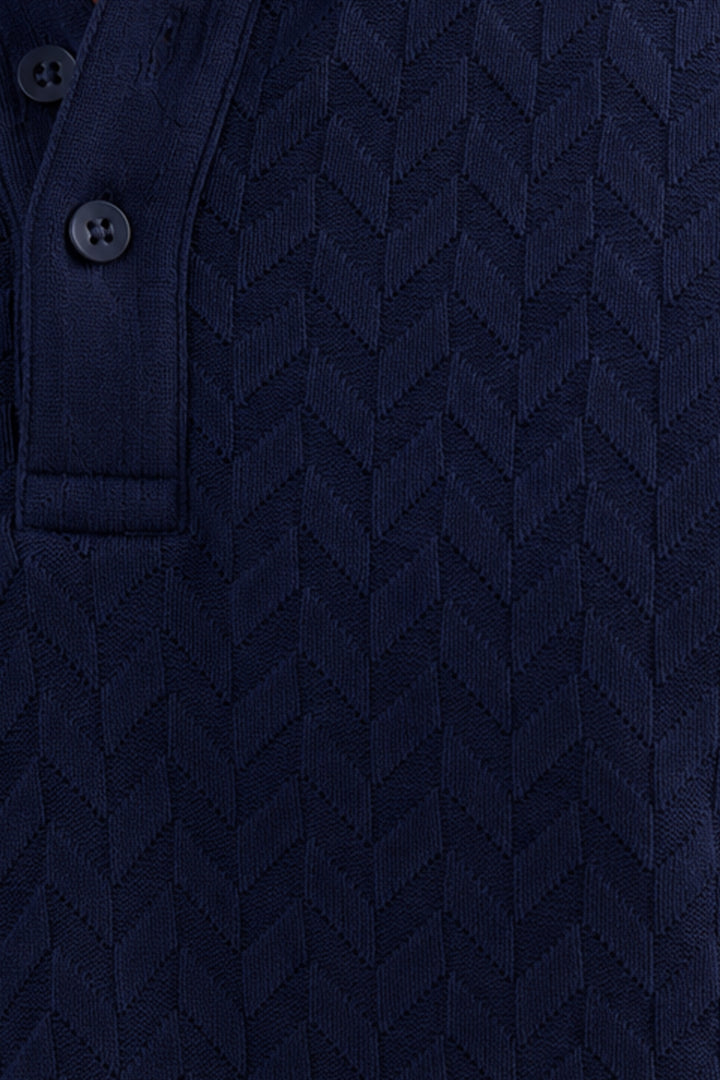 Close-up of a dark navy blue textured knit polo shirt showing a buttoned collar and a chevron pattern.
