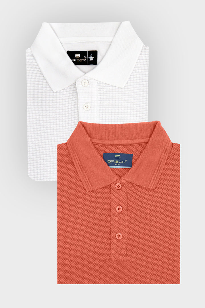 Two folded polo shirts from the brand Ariser shown on a light gray background. The top shirt is white with a subtle waffle texture, and the bottom shirt is a warm coral orange with a fine micro-dot pattern.