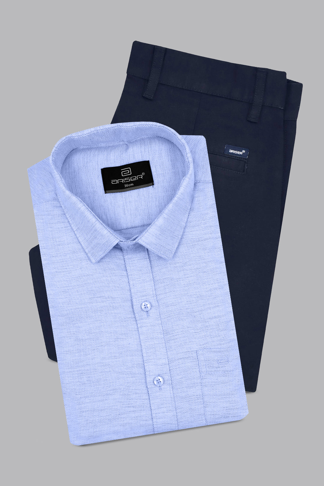 Folded light blue shirt and dark pants with brand labels on a gray background