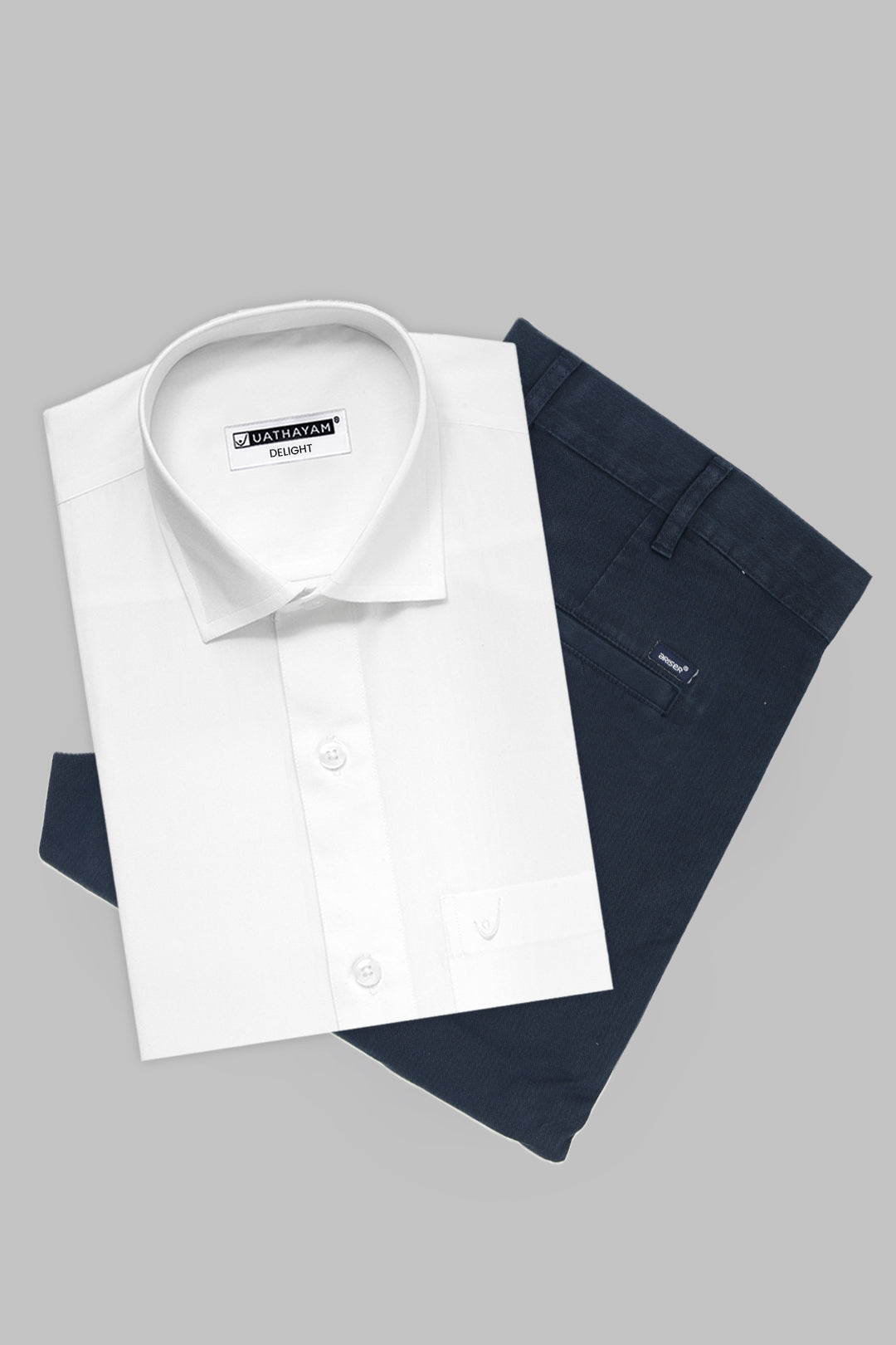 A folded white dress shirt with a pointed collar and button front, layered over folded navy trousers, on a plain light gray background. 