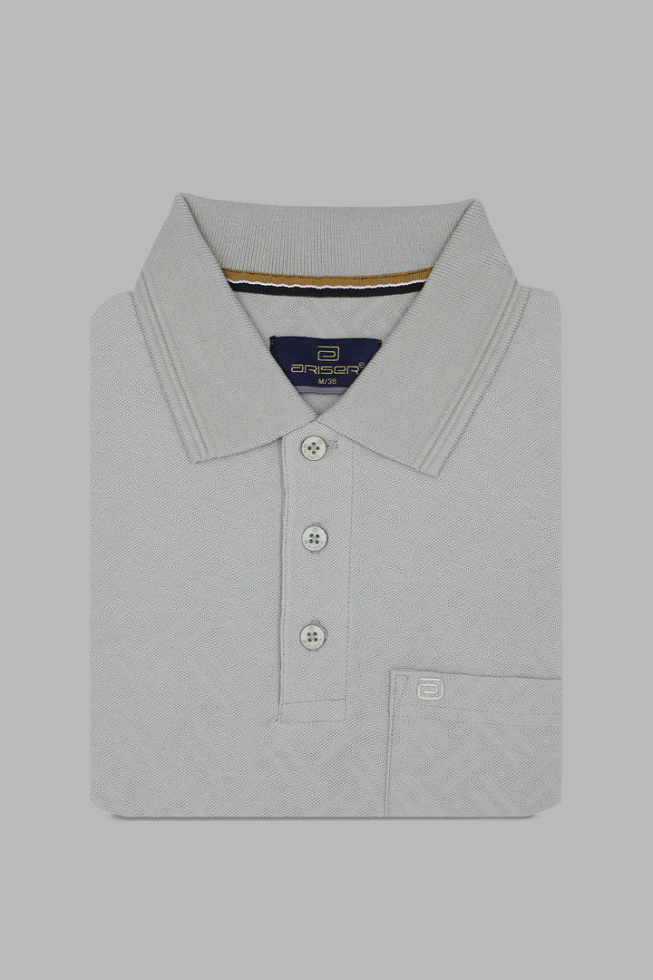 Folded light gray polo shirt with brand logo on a gray background