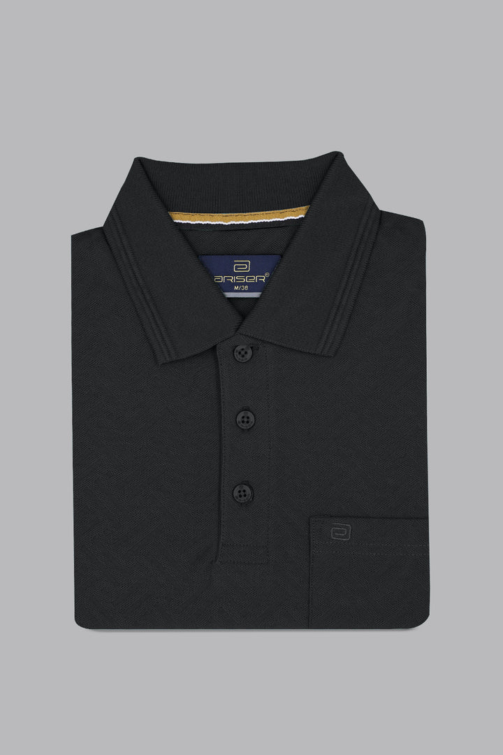 Folded black polo shirt with a brand label on a gray background