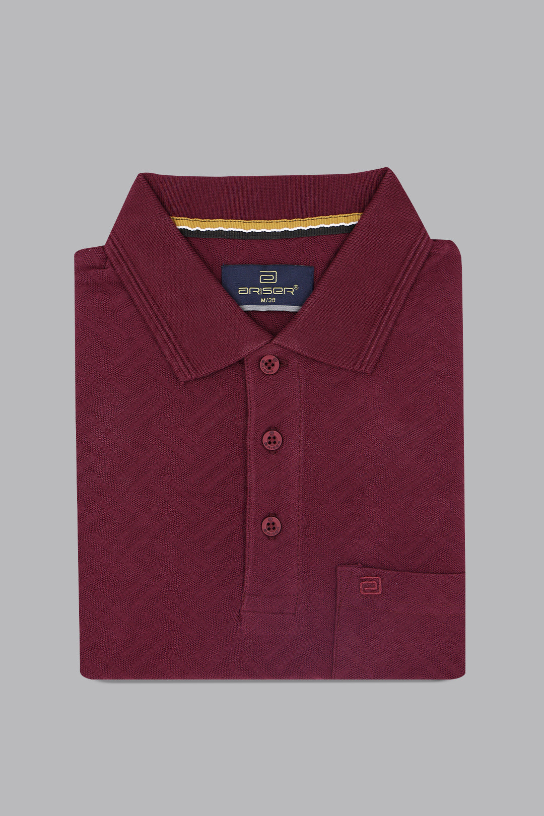 Folded maroon polo shirt with brand label on a gray background