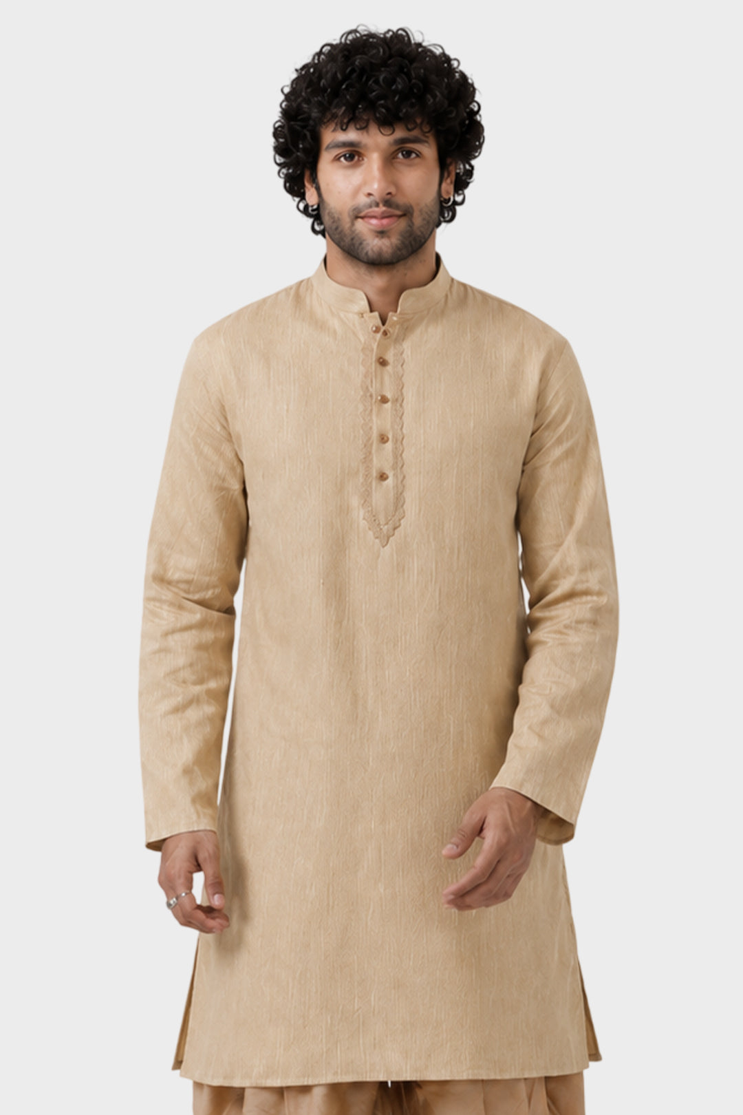 A man wearing a beige long-sleeve kurta with a mandarin collar and buttoned placket, photographed against a plain light gray studio background.