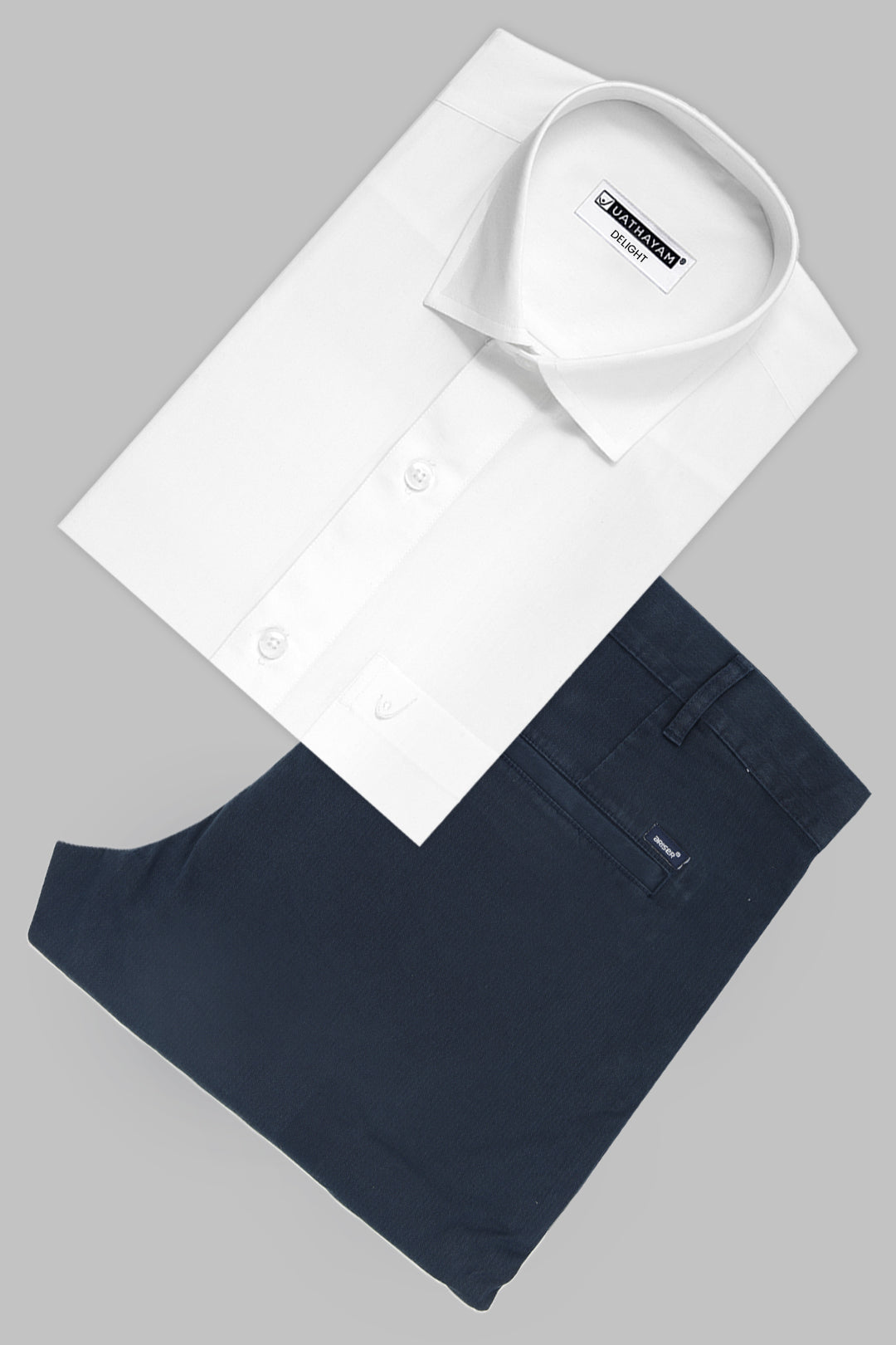 A white long-sleeve dress shirt and navy blue trousers neatly folded in a flat-lay arrangement on a solid gray background.