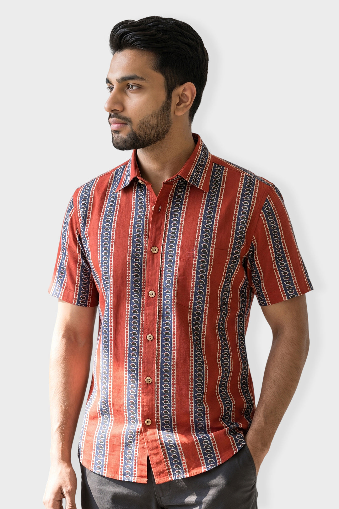 A man wearing a short-sleeve button-up shirt with vertical red, orange, and navy blue patterned stripes, posed against a light gray background.