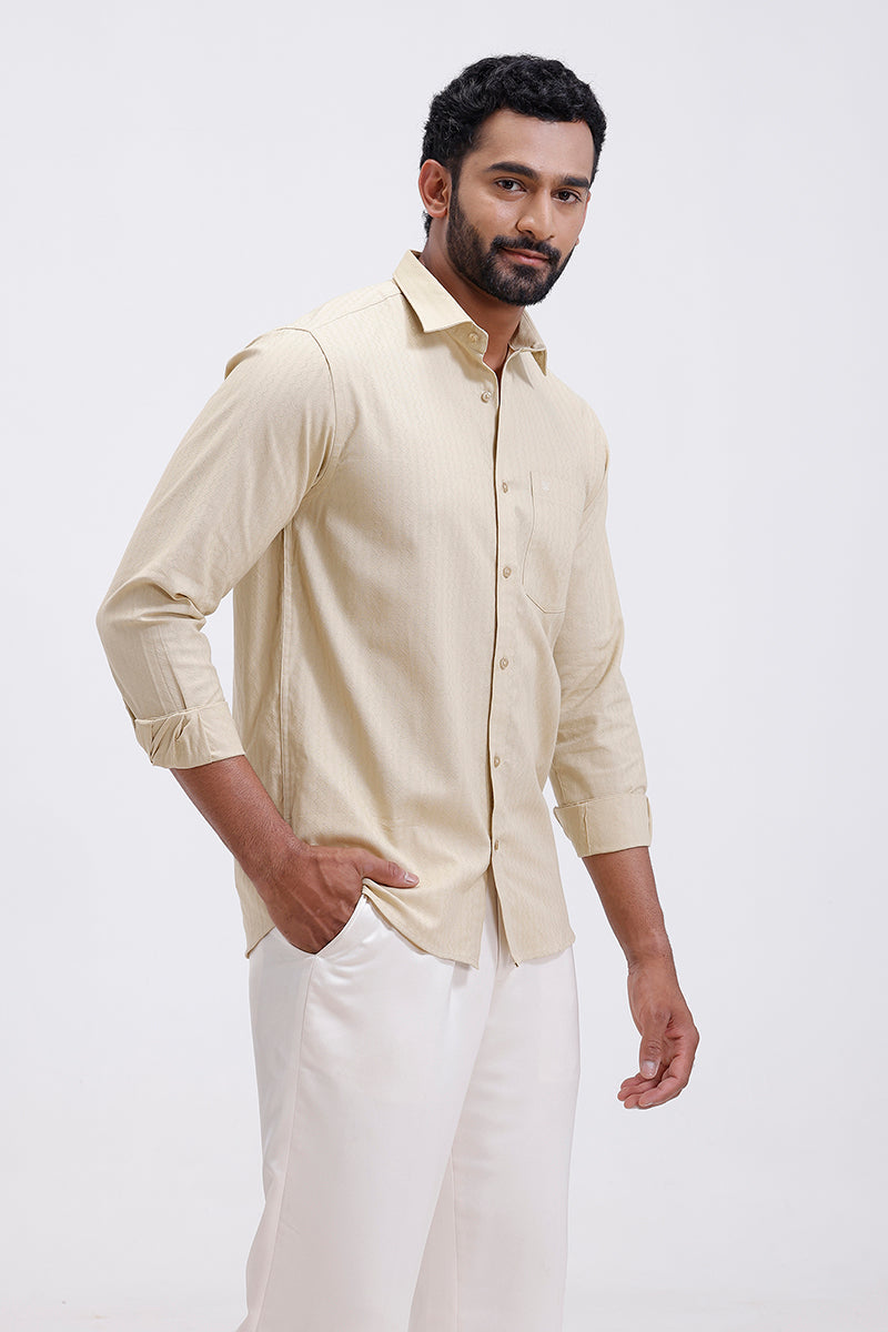 Man wearing a beige shirt and white pants on a light gray background