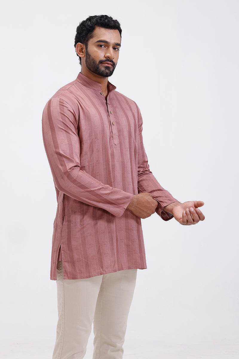 Man wearing a long kurta with white pants on a light gray background