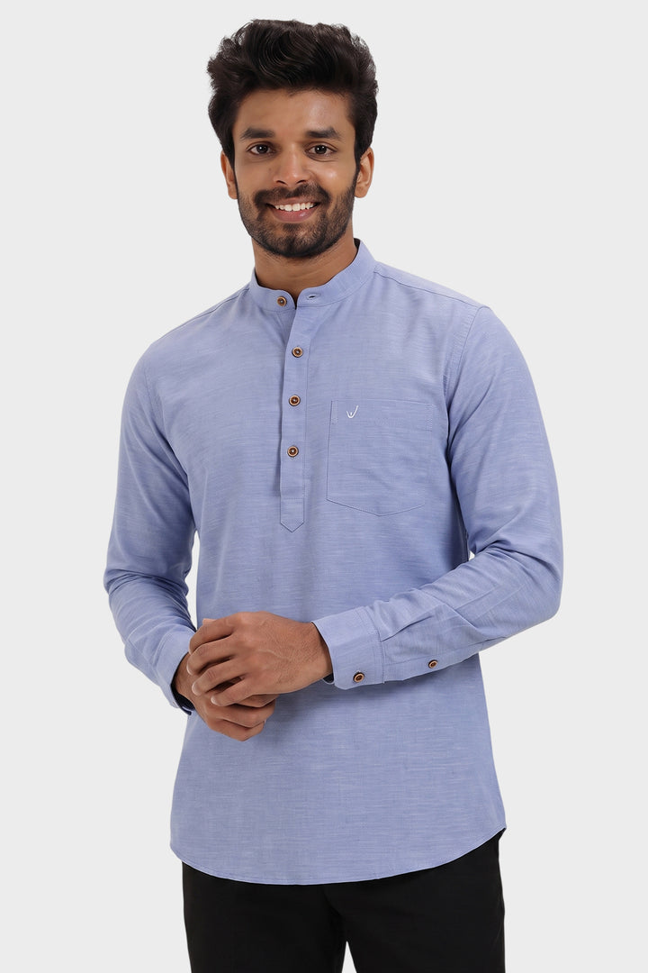 A man wearing a light blue long-sleeve mandarin collar shirt with a three-button placket and a chest pocket, paired with black pants, against a light gray background.