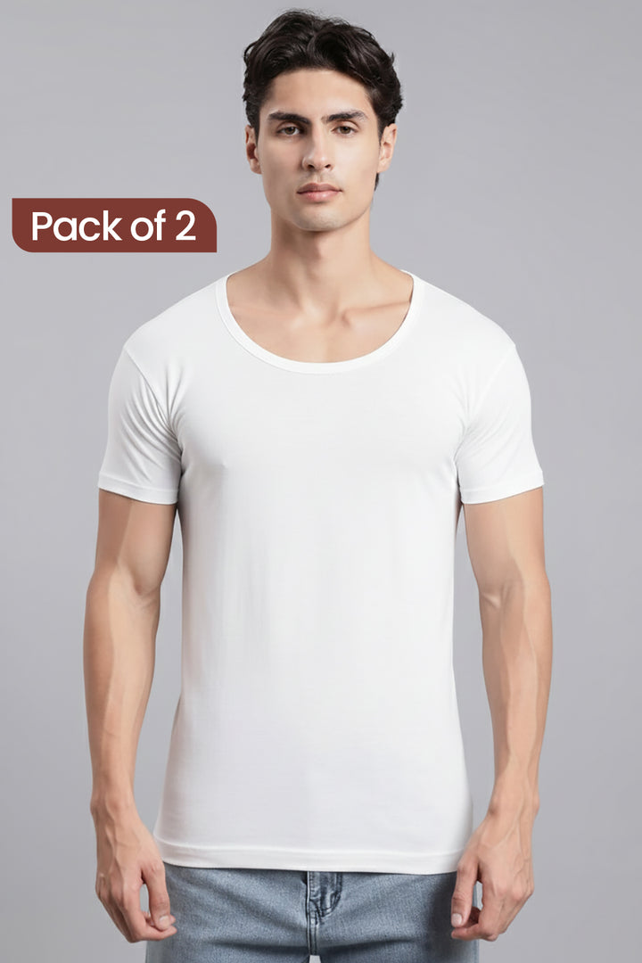 A man wearing a plain white short-sleeve crew-neck vest paired with light blue jeans, against a solid gray studio background. A brown label in the top-left corner reads 'Pack of 2'.