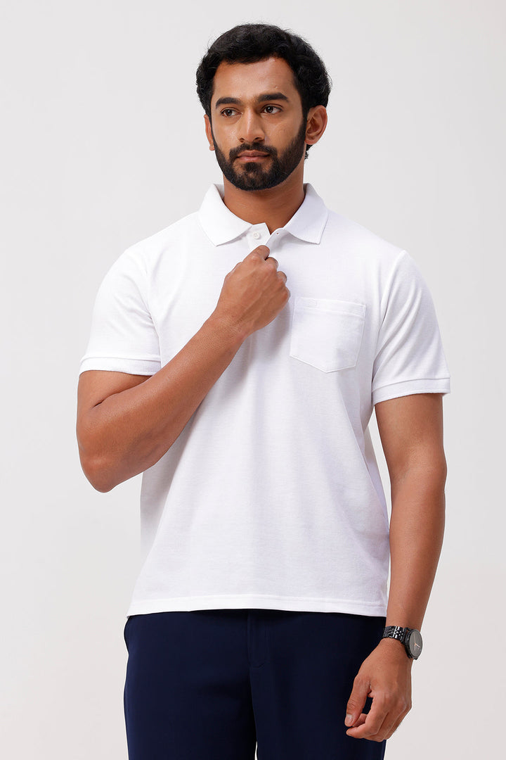 Man wearing a white polo shirt and dark pants on a light gray background