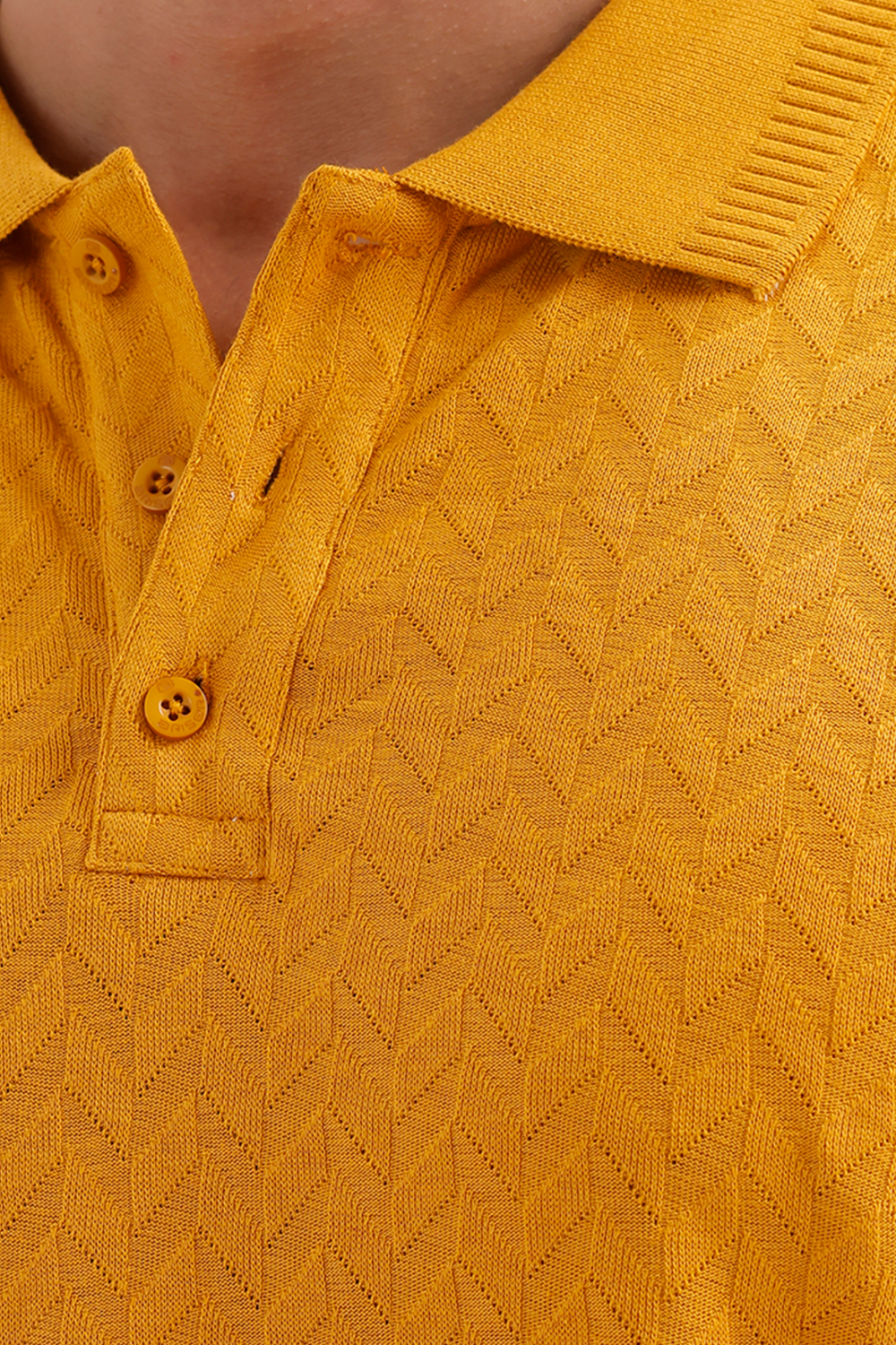 Close-up of a mustard yellow textured knit polo shirt with a ribbed collar and matching buttons, worn by a model.