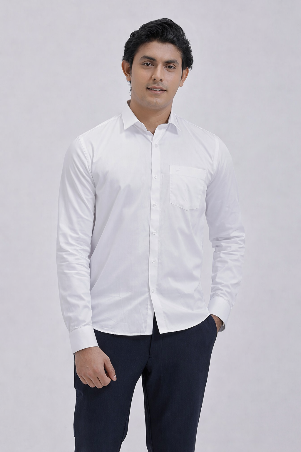 Man wearing a white dress shirt and dark pants against a plain background